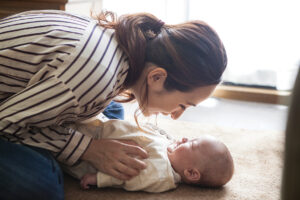A mother is gazing at a loving expression with a baby in his arms.