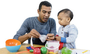 Father with baby sitting in the living room and having fun together