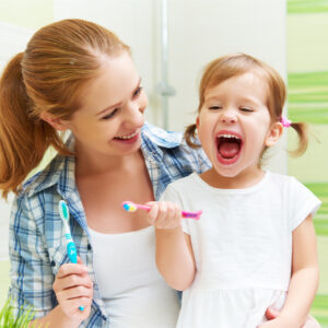 mum and child smiling and holding a toothbrush
