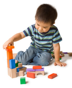 Little boy building a tower with colourful wooden blocks.